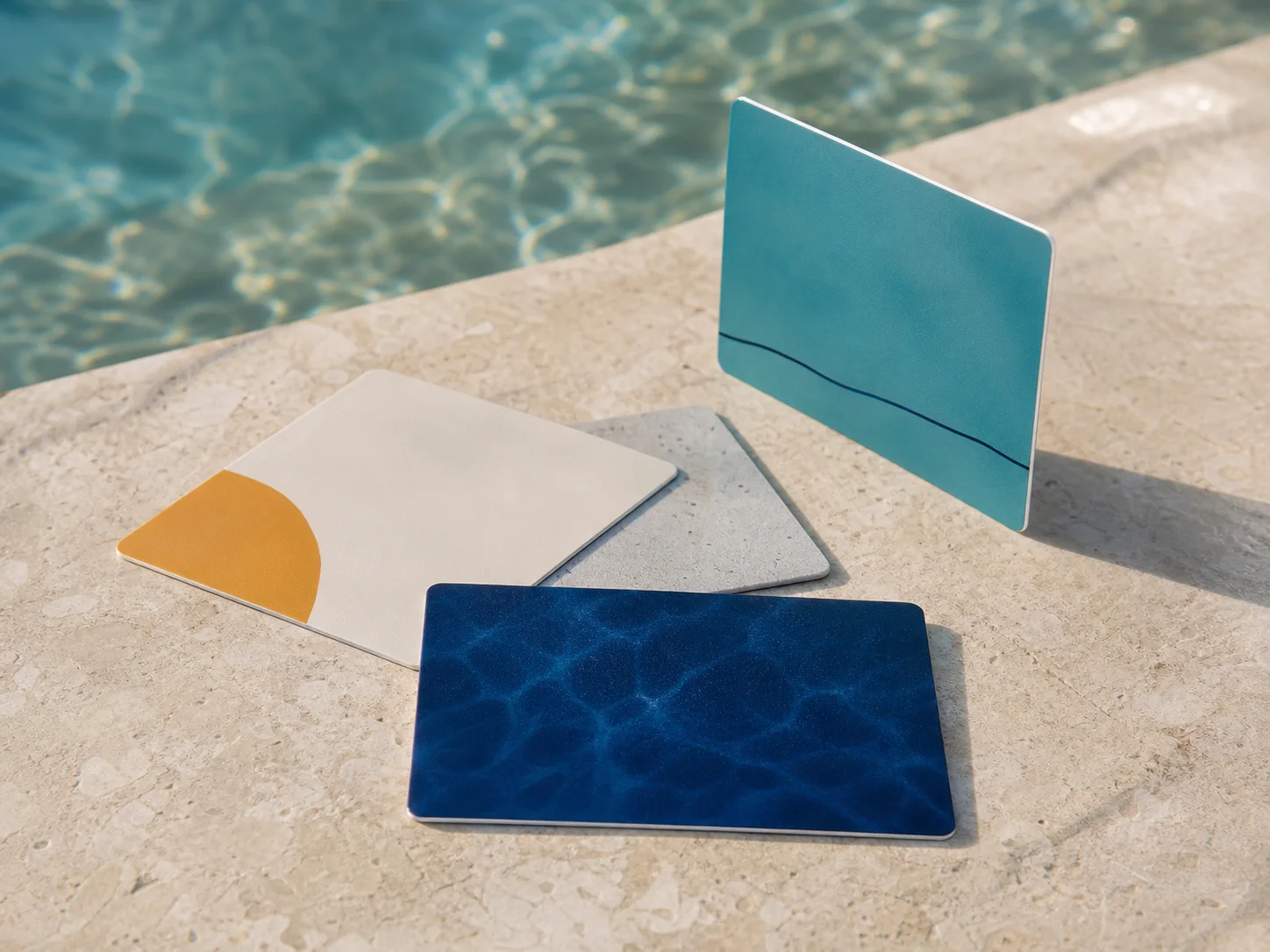 Four realistic unbranded hotel RFID key cards on pale stone beside turquoise Caribbean water